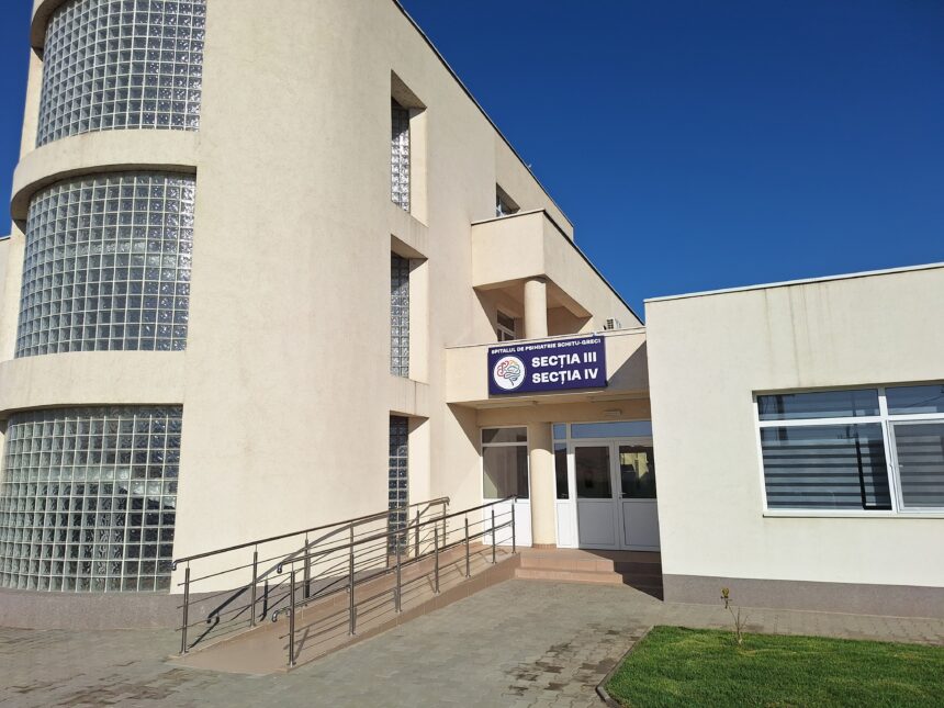 Beige modern hospital building with curved glass block windows and a ramp to the entrance.