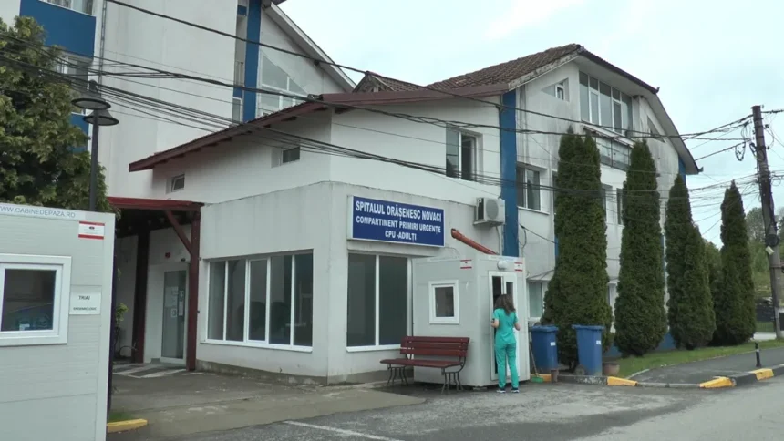 Hospital/clinic building with a blue sign for the emergency department; a medical staff member in teal scrubs stands by a small booth and bench near the entrance.