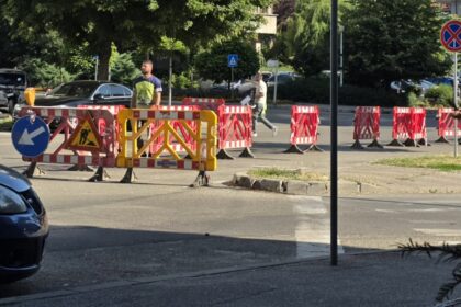 Construction site on a city street with red-and-white barriers and a yellow gate blocking traffic