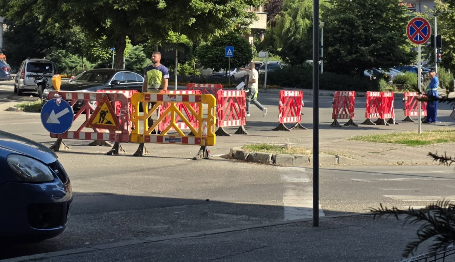 Construction site on a city street with red-and-white barriers and a yellow gate blocking traffic