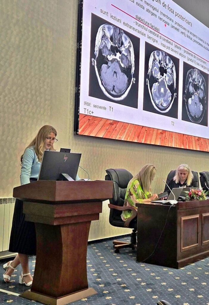 vertij conf - Jurnalul Olteniei – Știri din Craiova și Oltenia Woman speaks at a podium presenting medical slides; a large screen shows brain MRI images with two other panelists at a desk nearby.