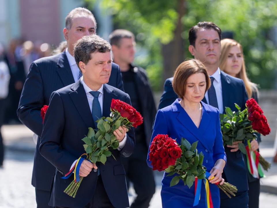 Group of formally dressed adults walking outdoors, each holding red roses for a ceremony or tribute.