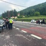 Police checkpoint on a two-lane road in a hilly, green landscape; officers with reflective vests and motorcycles are stopped as patrol carsmarked POLITIA observe nearby.