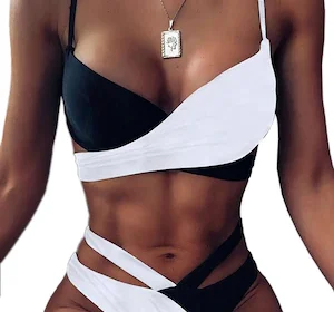 Woman in a black and white bikini with an asymmetric top and wrapped bottoms, wearing a pendant necklace.