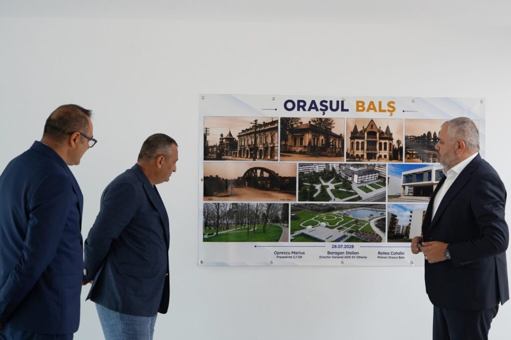Three men in suits examine a large poster titled Orașul Bals displaying a grid of city photos on a white wall.