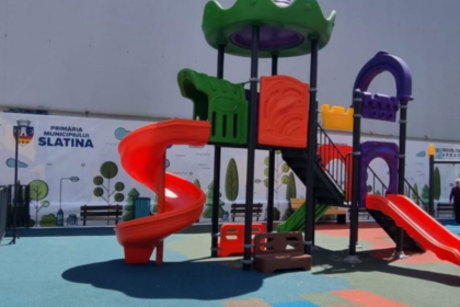 Colorful playground structure with red spiral slide, green and purple ramps, and a bright red straight slide in a sunny outdoor park area.