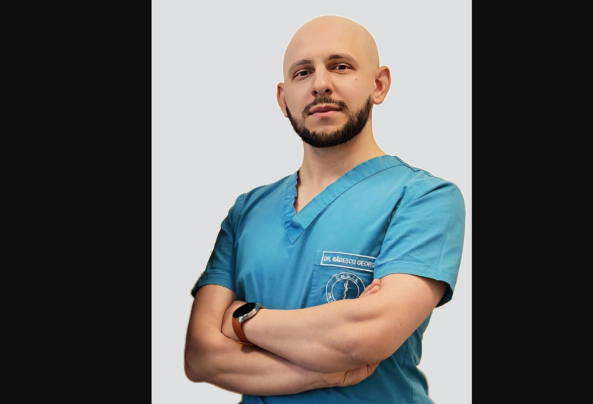 Male doctor in teal scrubs with arms crossed, wearing a smartwatch against a light gray backdrop