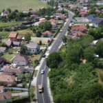 Aerial view of a rural town with a curving road running between houses and green fields on either side.