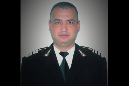 Portrait of a man in a dark formal uniform with a black tie, facing the camera.