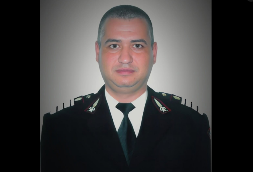 Portrait of a man in a dark formal uniform with a black tie, facing the camera.