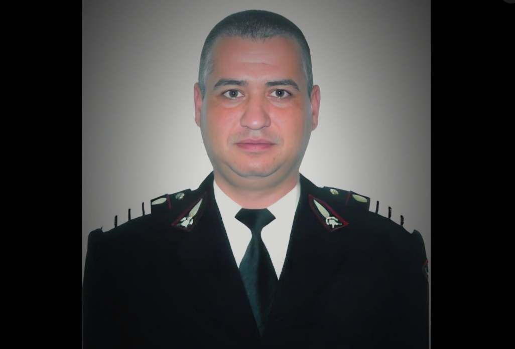 Portrait of a man in a dark formal uniform with a black tie, facing the camera.