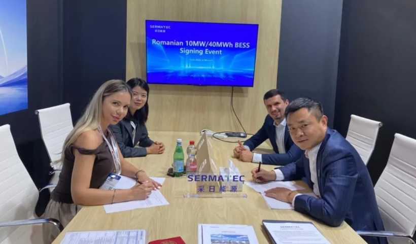 Signing ceremony at a conference table with four professionals signing documents; screen behind reads 'Romanian 10MW/40MWh BESS Signing Event'.
