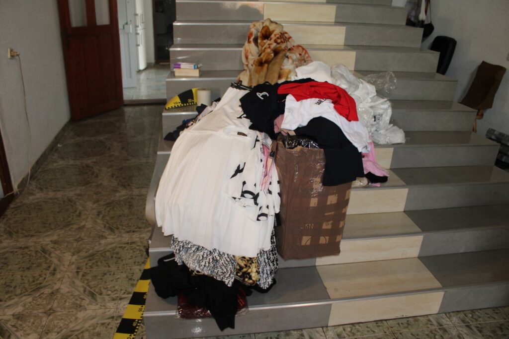 Clothes and a cardboard box piled on a staircase, creating clutter in a living space.