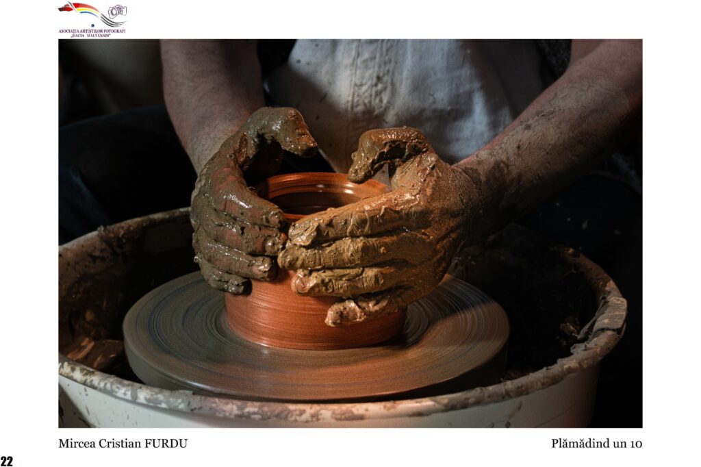Close-up of muddy hands shaping a clay pot on a spinning pottery wheel, pottery wheel and clay visible around the hands.