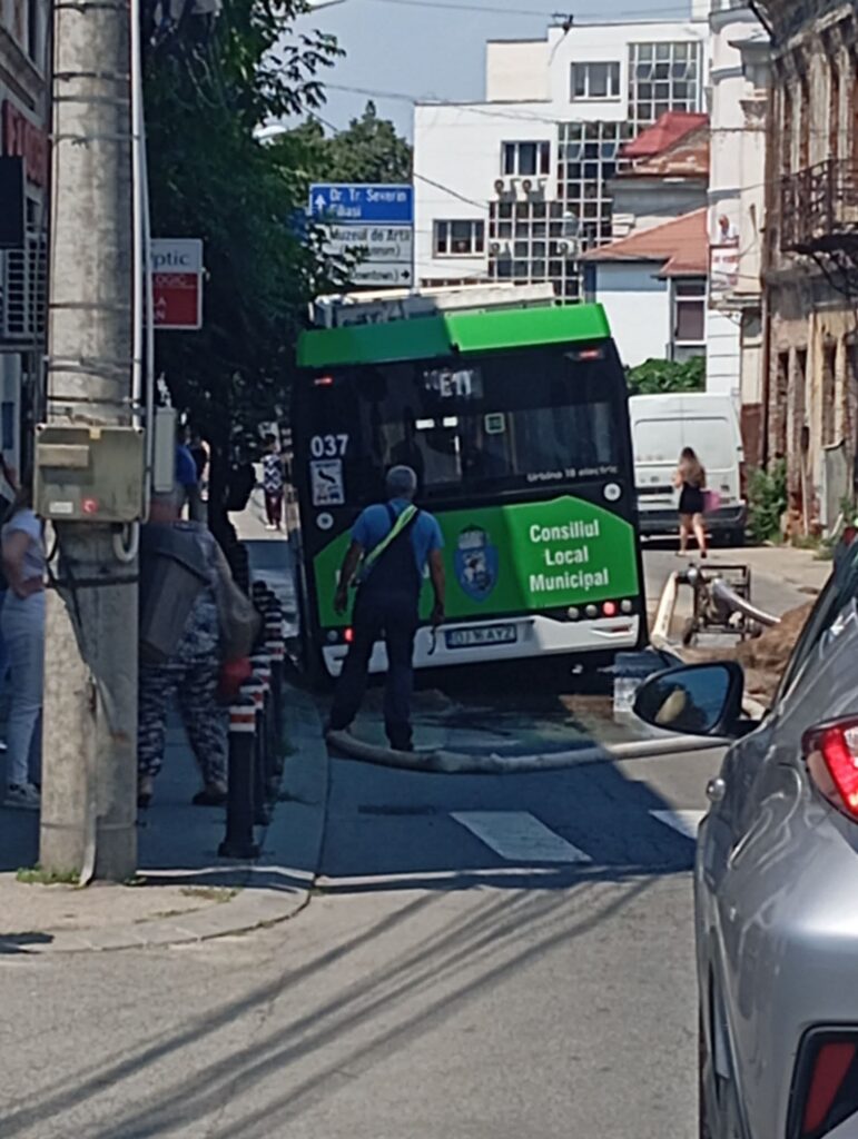 asfalt autobuz 2 WhatsApp Image 2026-07-03 at 142740 - Jurnalul Olteniei – Știri din Craiova și Oltenia Green and black municipal bus on a narrow city street, with pedestrians on the sidewalk and classic buildings in the background.