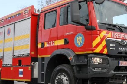 Front and side view of a red fire engine with yellow chevrons and 'POMPIERII' on the side, parked on a road.