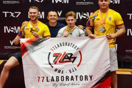 Four men pose on a competition stage with medals; two wear yellow shirts, one in white, holding a banner that says '77 Laboratory MMA - BJJ'.