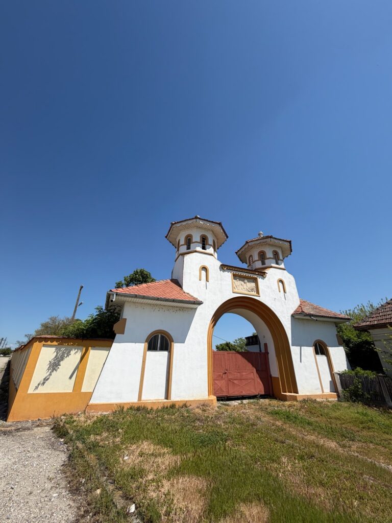 conacul romano plesoiu 12 - Jurnalul Olteniei – Știri din Craiova și Oltenia White church entrance with orange trim and two domed towers beneath a clear blue sky.