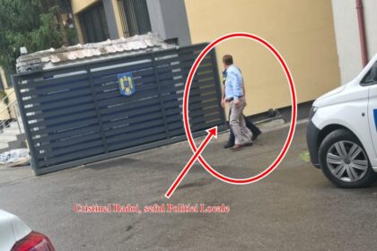 Man in a light blue shirt walks along a street beside a dark metal gate with a white police van nearby; the person is circled by a red outline and arrow and highlighted for emphasis.