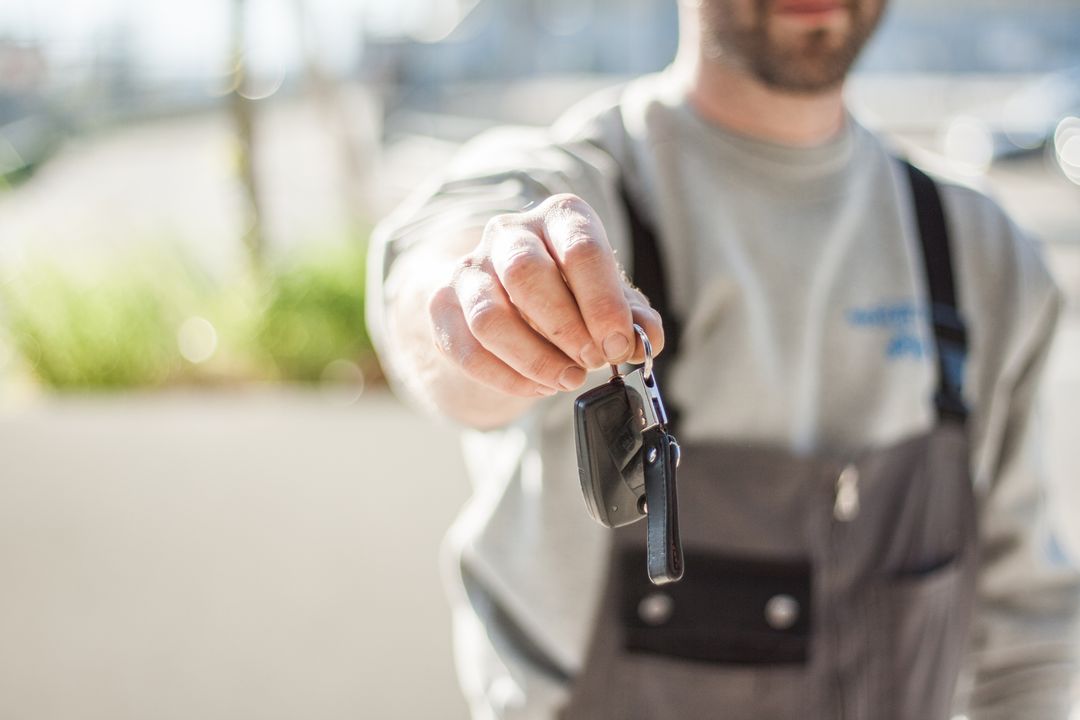 inchiriere auto pexels-negativespace-97075 - Jurnalul Olteniei – Știri din Craiova și Oltenia Person in gray shirt and overalls holds out car keys toward the camera (handing over keys).