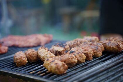 Grilled meatballs cooking on a barbecue grill outdoors.