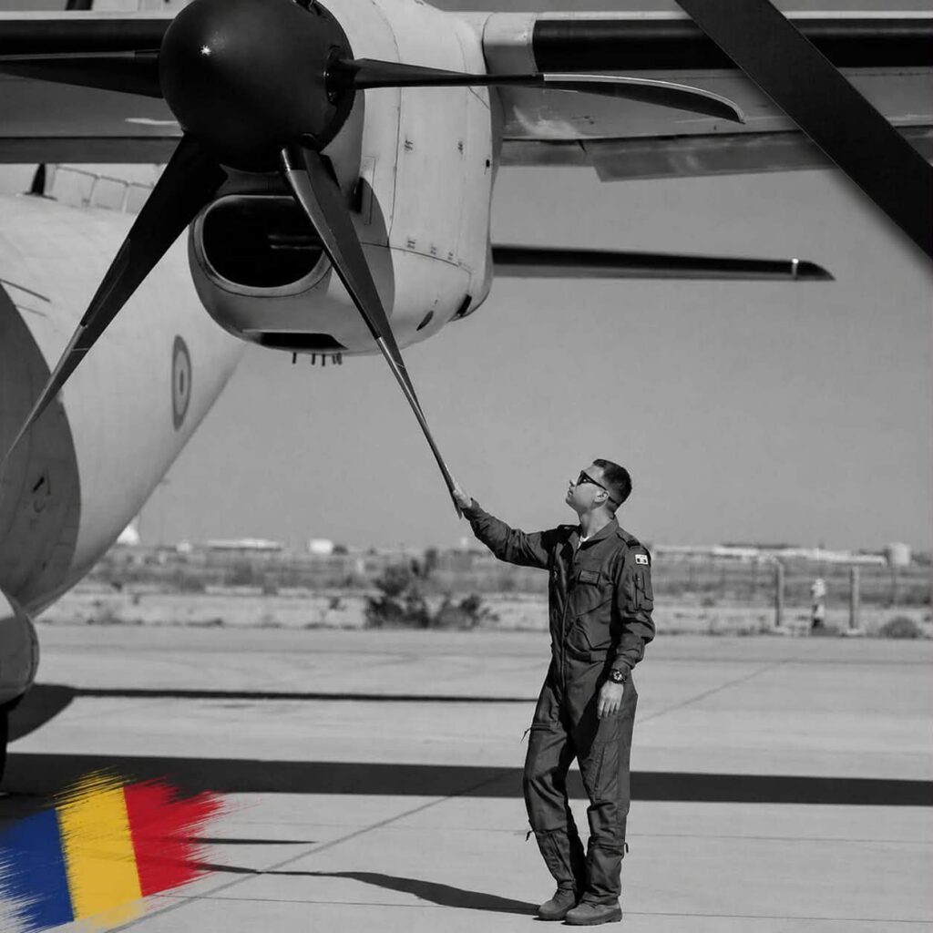 mihai virdol - Jurnalul Olteniei – Știri din Craiova și Oltenia Ground crew member in a flight suit guides a propeller aircraft on the tarmac, gripping a line toward the engine nacelle.