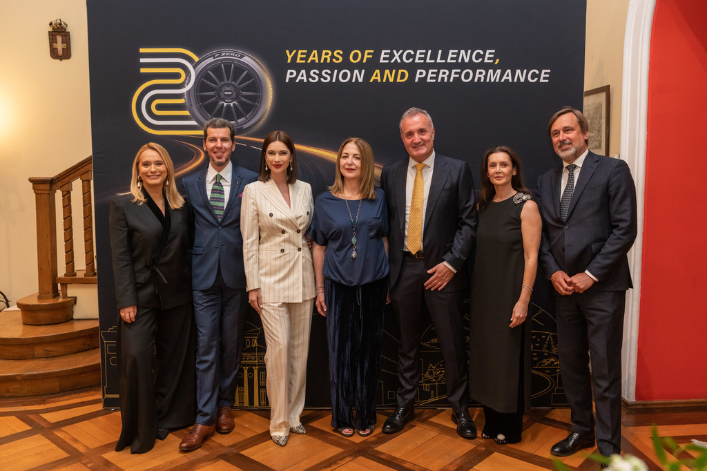 Seven professionals in formal attire pose for a group photo in front of a dark banner reading'Years of Excellence, Passion and Performance'.