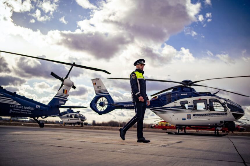 Police officer in uniform walking on a helicopter pad with blue-and-white government helicopters in the background.