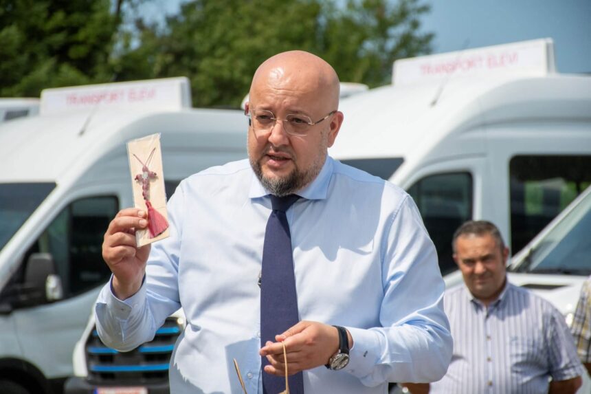 Bald man in a blue shirt and tie holding a packaged meat skewer outdoors, with a white van in the background.