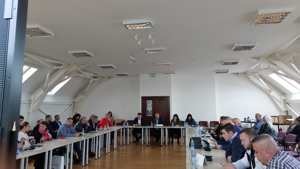 20250130_140456 - Jurnalul Olteniei – Știri din Craiova și Oltenia Meeting in a bright conference room with attendees seated around long tables in a U shape, papers and water bottles in front of them.