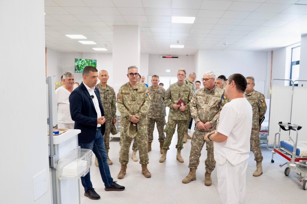 - Jurnalul Olteniei – Știri din Craiova și Oltenia Group of soldiers in camouflage with a man in a navy blazer speaking in a bright clinical hallway.