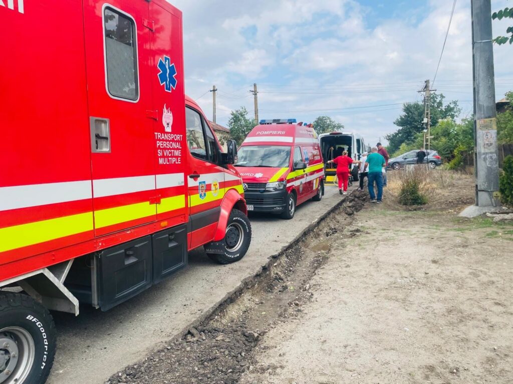 Red emergency vehicles (ambulance and fire brigade) parked on a rural road while people assist nearby fall‑back scene behind them.