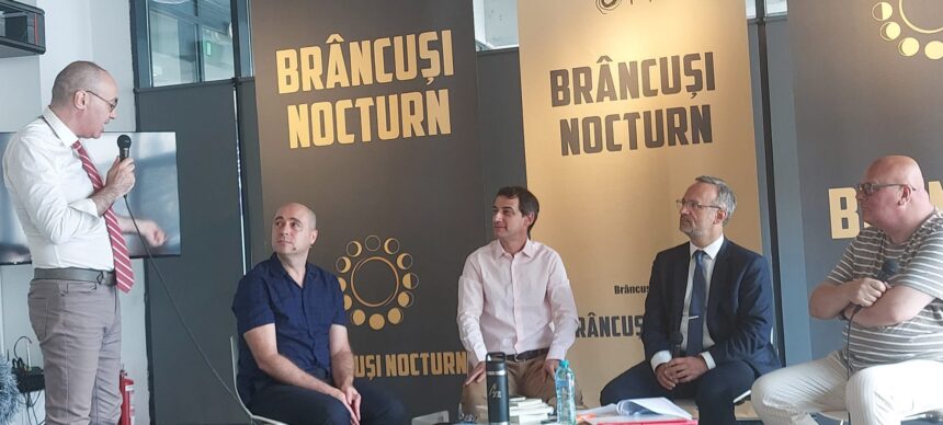 Speaker in a white shirt and red striped tie addresses a panel of four men, with large Brâncuși Nocturn banners behind them.