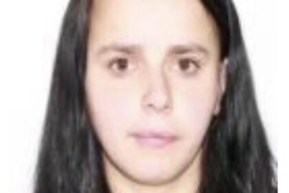 Portrait of a young woman with long dark hair facing the camera against a white background, neutral expression.