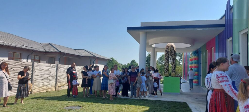 - Jurnalul Olteniei – Știri din Craiova și Oltenia Crowd of people, including children in festive clothing, gathers outside a colorful modern building with balloon decorations in a sunny yard.