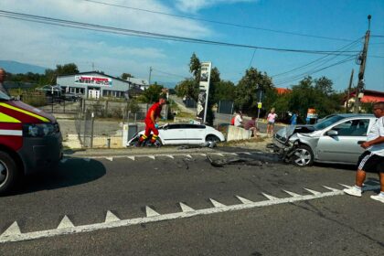 Emergency responders and bystanders at a road collision with a damaged white car and debris on the pavement. wires overhead.