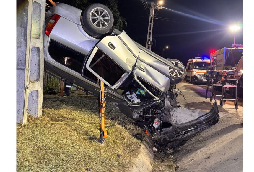 Nighttime crash scene: a silver SUV crushed against a guardrail, debris on the road, emergency crews and vehicles in the background.