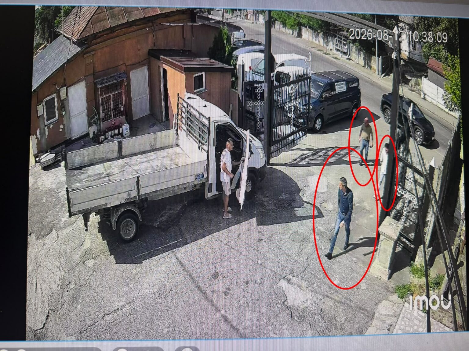 Man steps out of a white delivery truck with its cab door open on a sunny urban street.