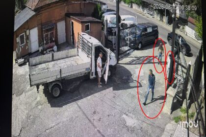 Man steps out of a white delivery truck with its cab door open on a sunny urban street.