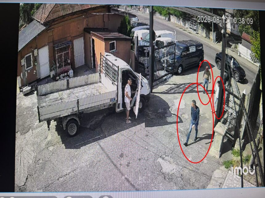Man steps out of a white delivery truck with its cab door open on a sunny urban street.