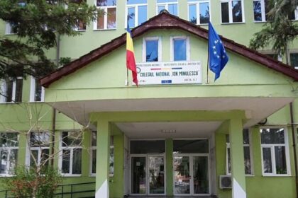 Green school building with a covered entrance, Romanian and EU flags on the roof, and a sign identifying Colegiul National Ion Minulescu above the entry.