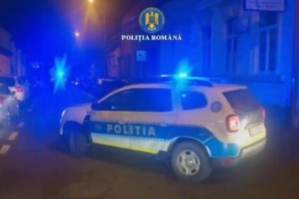 Romanian police SUV with blue flashing lights on a dim street at night; Poliția Română emblem visible on the car.