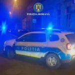 Romanian Police car with blue flashing lights on a nighttime urban street.