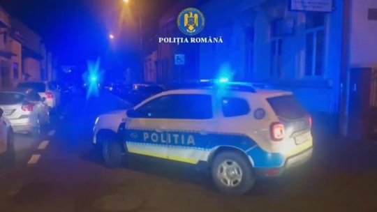 Romanian Police car with blue flashing lights on a nighttime urban street.