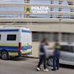 Romanian police van and marked patrol car parked outside a modern building; three blurred individuals stand nearby.