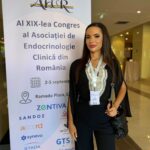 Woman standing next to a conference banner for AI XIX-lea Congres al Asociatiei de Endocrinologie Clinica din Romania, wearing a lanyard badge.