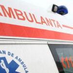 Ambulance with red stripe and the word 'AMBULANȚA' on the side, blue emergency light on top, 112 visible on the window side (Romanian emergency vehicle).