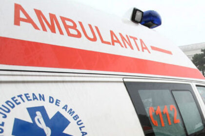 Ambulance with red stripe and the word 'AMBULANȚA' on the side, blue emergency light on top, 112 visible on the window side (Romanian emergency vehicle).