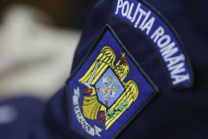 Close-up of a Romanian Police patch on a dark blue uniform, showing a yellow eagle emblem and blue shield with a banner that reads 'POLIȚIA ROMANA' in white letters.