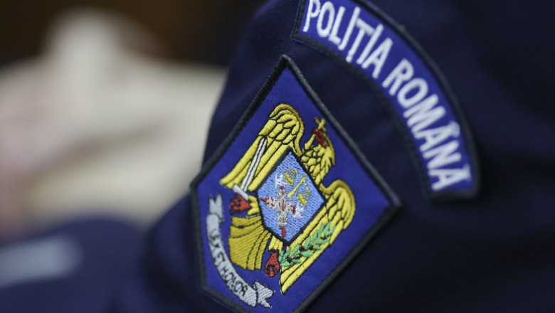 Close-up of a Romanian Police patch on a dark blue uniform, showing a yellow eagle emblem and blue shield with a banner that reads 'POLIȚIA ROMANA' in white letters.